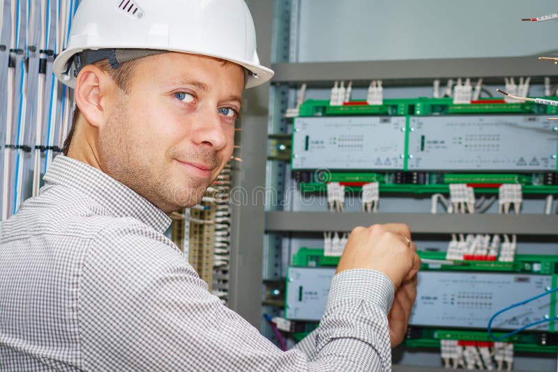 Engineer tests industrial electrical circuits in control terminal box. Electrician adjusts electric equipment in automation panel. stock images