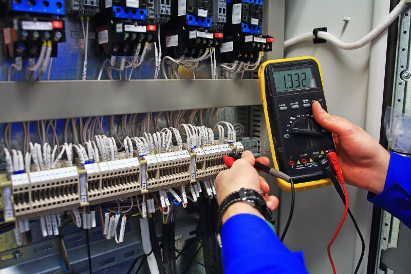 Engineer tests industrial electrical circuits with a multimeter in the control terminal box royalty free stock images