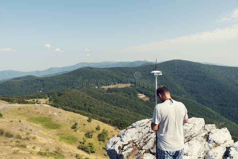 Engineer Using GPS Surveying Equipment in Mountain during the Summer