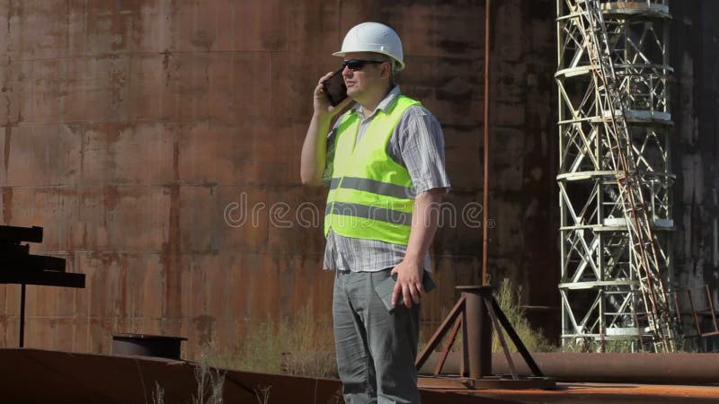 Engineer using smartphone near to the tanks