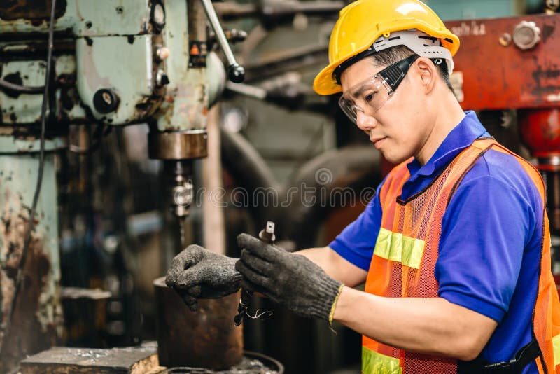 Engineer worker checking and replace a drill bit of metal drilling machine in heavy industry factory