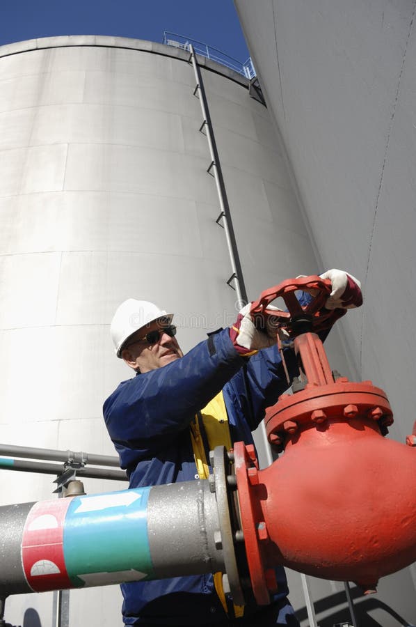 Gli ingegneri che lavorano all'interno di petrolio e gas di raffineria, condotte e pompe, girando una manovella sulla pipeline.