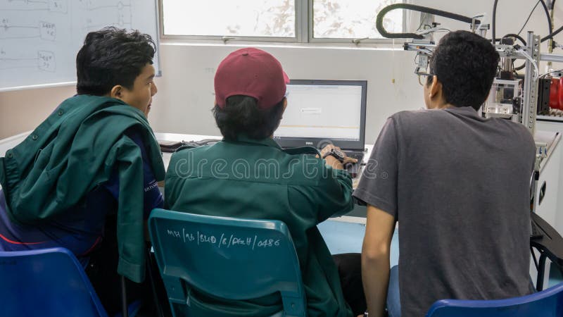 Engineering students discussing and solving the task given on the automation machine system in the laboratory stock photo