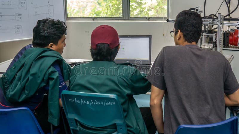 Engineering students discussing and solving the task given on the automation machine system in the laboratory stock photos