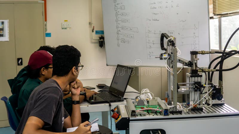 Engineering students discussing and solving the task given on the automation machine system in the laboratory royalty free stock photography