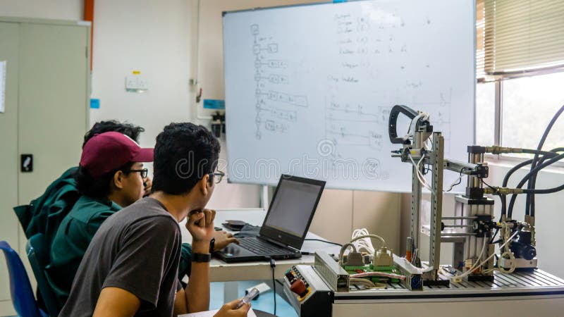 Engineering students discussing and solving the task given on the automation machine system in the laboratory royalty free stock photos