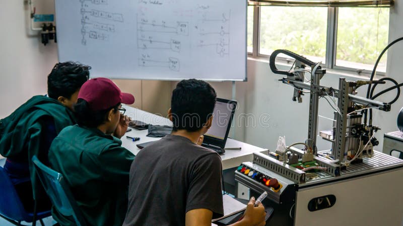 Engineering students discussing and solving the task given on the automation machine system in the laboratory stock photo