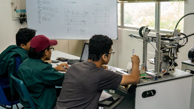 Engineering students discussing and solving the task given on the automation machine system in the laboratory royalty free stock photo