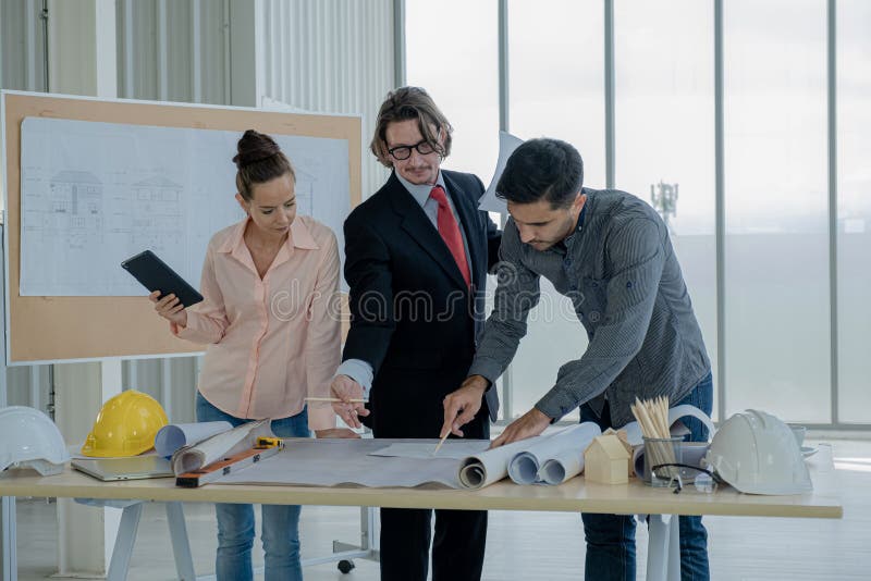 The engineering team are meeting to inspect the construction drawings, plan work and distribute work before starting the royalty free stock photography