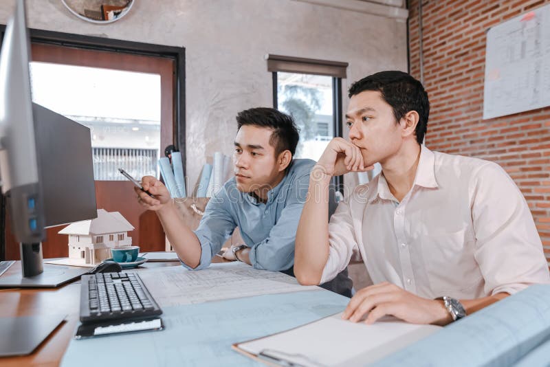 Engineers and architect reading a building and  drawing outlay construction plan as guide for builders with details on computer.