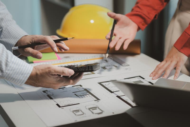 Engineers and colleagues are working to calculate the space in the various rooms of the blueprint to create a solution that meets royalty free stock photography