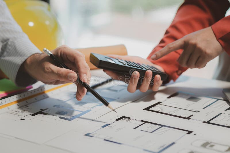 Engineers and colleagues are working to calculate the space in the various rooms of the blueprint to create a solution that meets royalty free stock photo