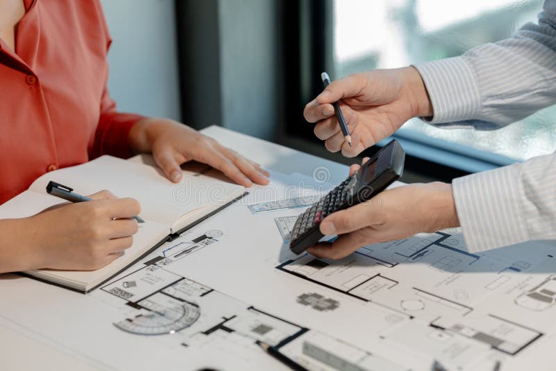 Engineers and colleagues are working to calculate the space in the various rooms of the blueprint to create a solution that meets royalty free stock image