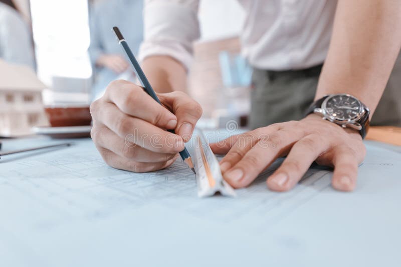 engineers holding a pen pointing to a building and drawing outlay construction plan as guide for builders with details. Engineer