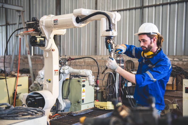 Engineers mechanic using computer controller Robotic arm for welding steel in steel factory workshop. Industry robot programming stock image
