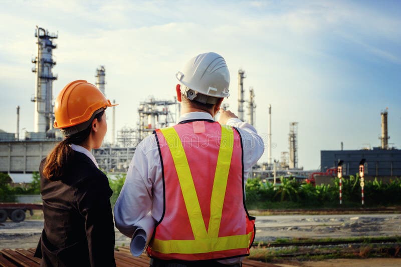 The engineers are standing on large industry background. stock photo