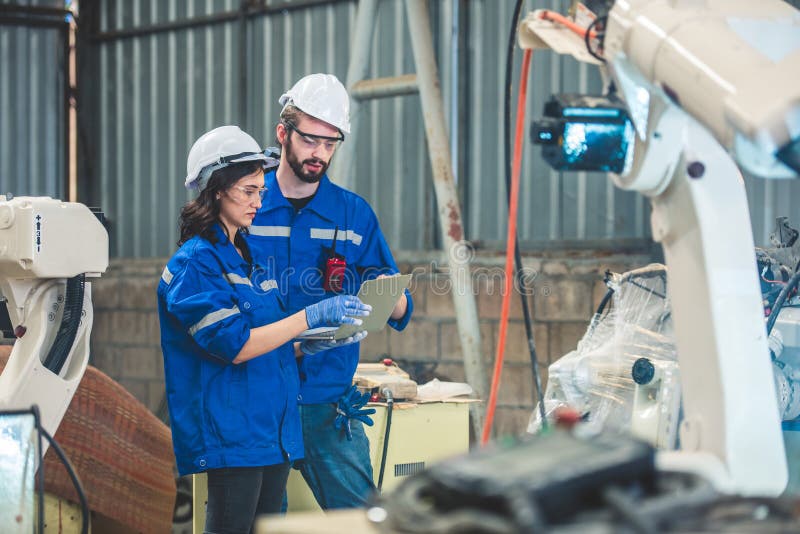 Engineers team mechanic using computer controller Robotic arm for welding steel in steel factory workshop. Industry robot royalty free stock photo