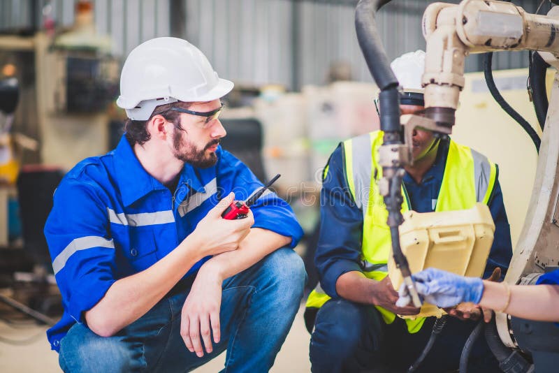 Engineers team mechanic using computer controller Robotic arm for welding steel in steel factory workshop. Industry robot stock images