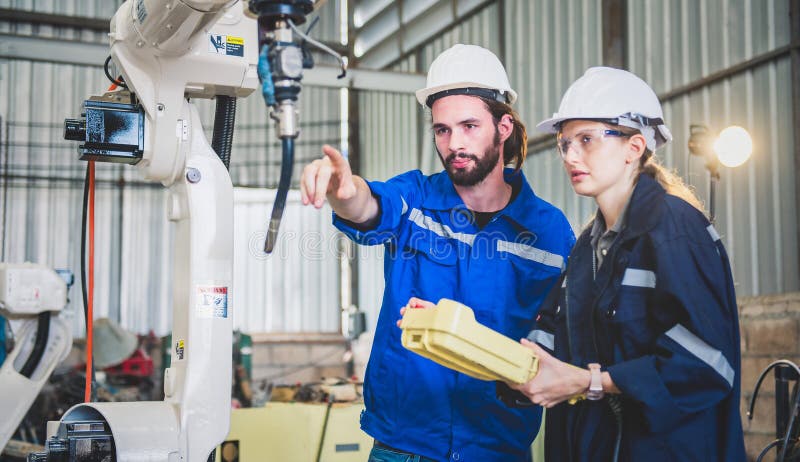 Engineers team mechanic using computer controller Robotic arm for welding steel in steel factory workshop. Industry robot stock photography