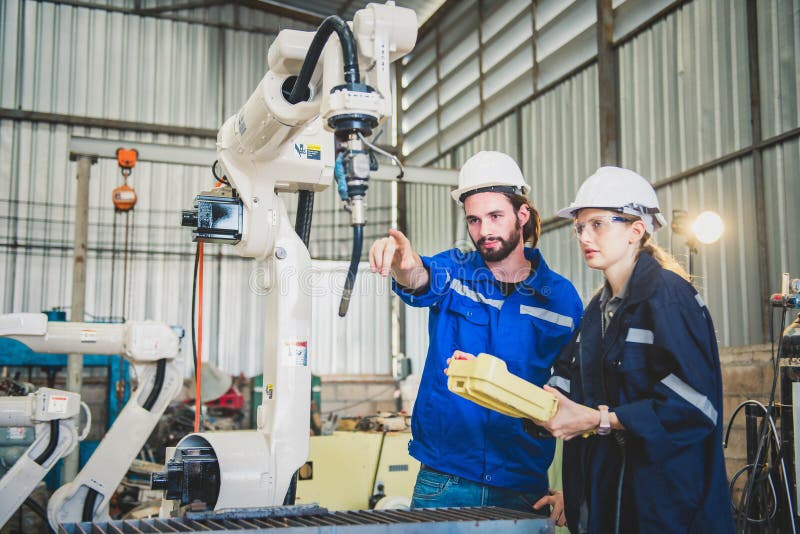Engineers team mechanic using computer controller Robotic arm for welding steel in steel factory workshop. Industry robot stock photo