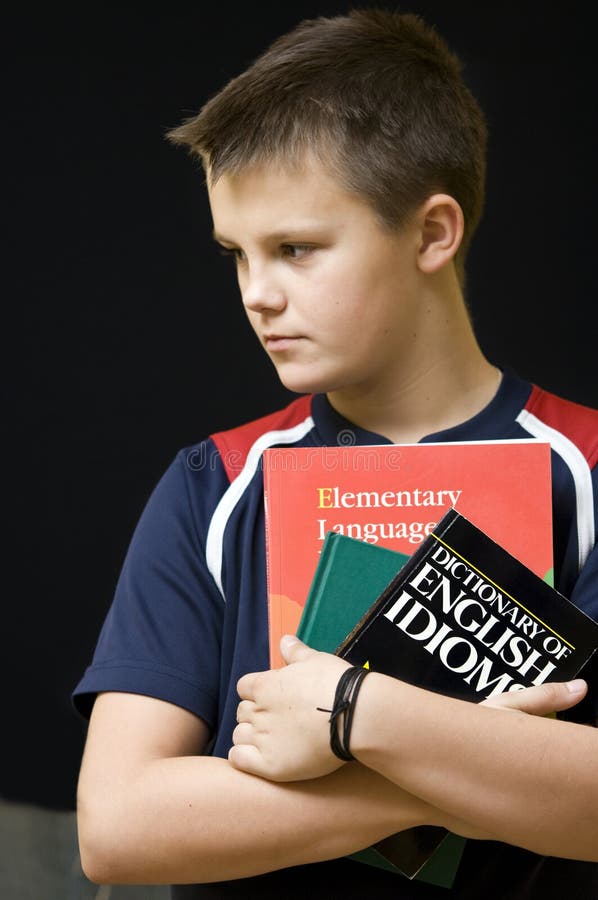 Portrait of a young teenage boy holding his school English language books. Black background. Boring kid white stock images, royalty-free photos and pictures