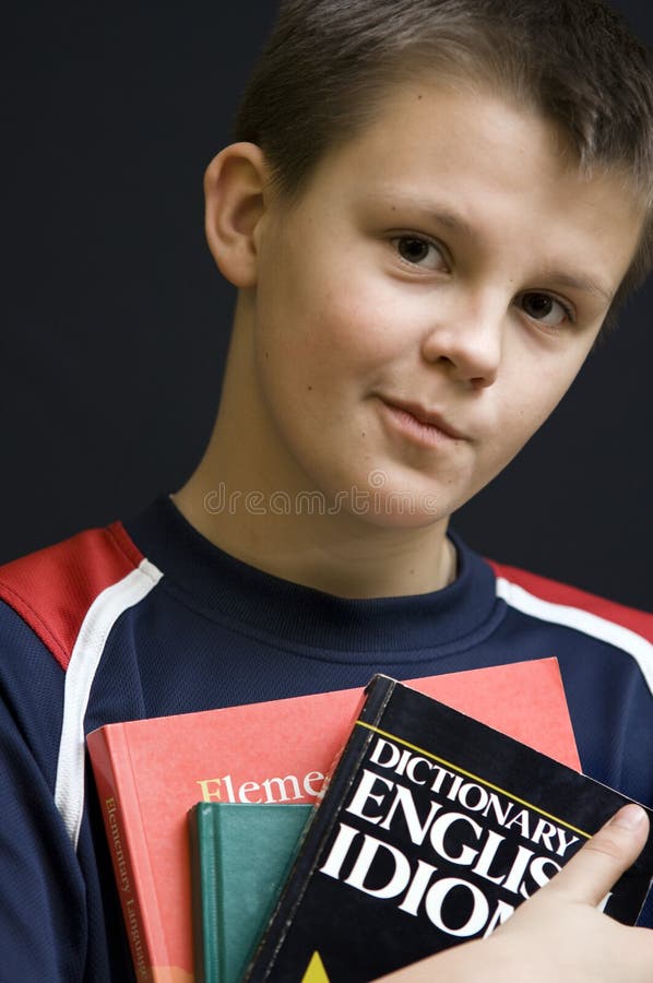 Portrait of a young teenage boy holding his school English language books. Black background. Boring kid white stock images, royalty-free photos and pictures