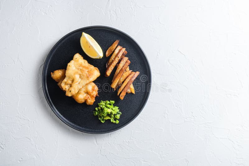 English traditional food fish and chips with peas and a slice of lemon top view