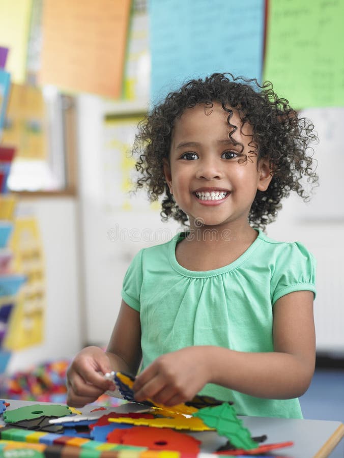 Enigmas de montagem da menina na sala de aula fotografia de stock Enigmas de montagem da menina na sala de aula fotografia de stock