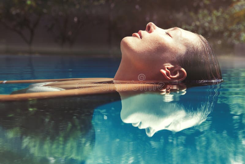 Mujer hermosa flotante en el agua en nadar piscina.