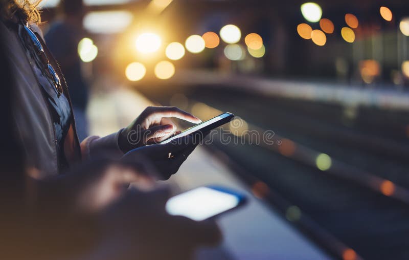 Enjoying travel. Young woman waiting on station platform on background light electric moving train using smart phone in night royalty free stock photos Enjoying travel. Young woman waiting on station platform on background light electric moving train using smart phone in night royalty free stock photos