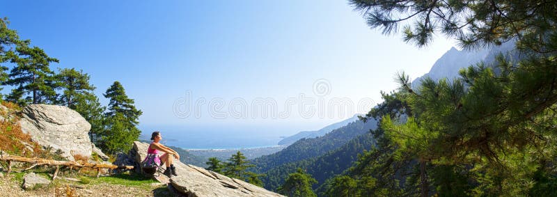 Beautiful fit young woman taking a break and enjoying the view of the mountain at the island of Thassos, Greece.