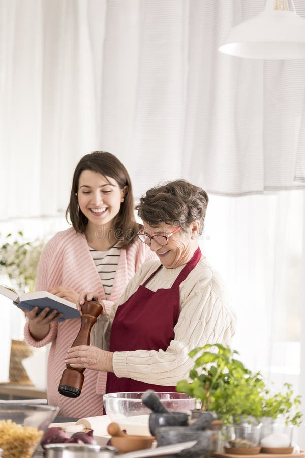 Enkelinlesegroßmutterrezepte lizenzfreies stockfoto Enkelinlesegroßmutterrezepte lizenzfreies stockfoto