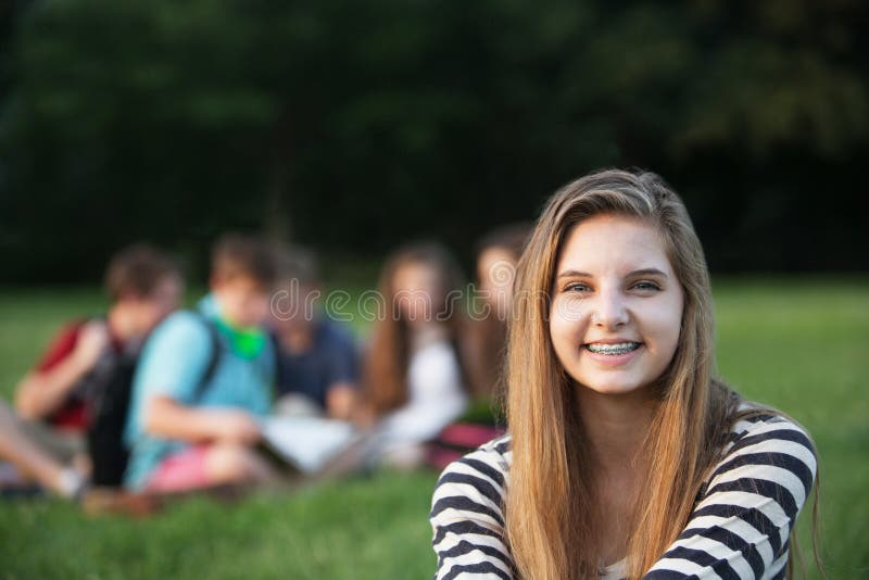 Cute smiling teenage girl with braces sitting outdoors. Cute smiling teenage girl with braces sitting outdoors