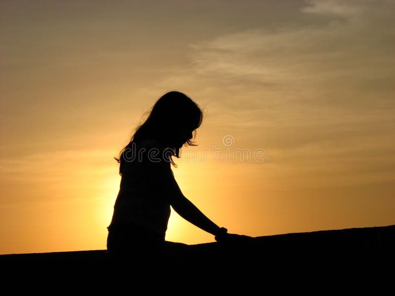 An Indian hindu woman sitting calmly after meditating on the sun at sunrise. Sun is treated as a god in hindu religion. An Indian hindu woman sitting calmly after meditating on the sun at sunrise. Sun is treated as a god in hindu religion