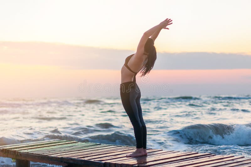 Enlightened Young woman relaxing on the beach, meditating in asana hasta uttanasana, with hands In Namaste gesture at