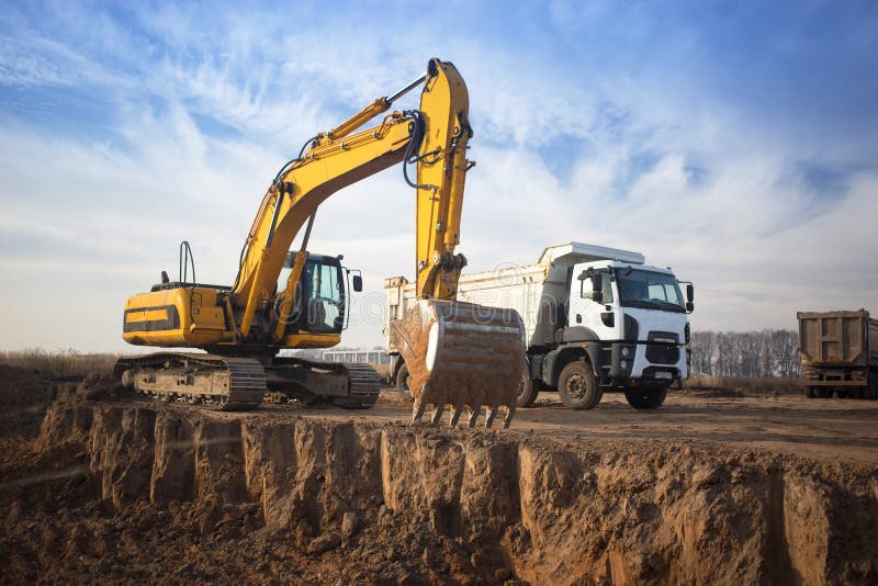 Enorme excavadora de rastreo amarillo y un camión de vertederos de construcción