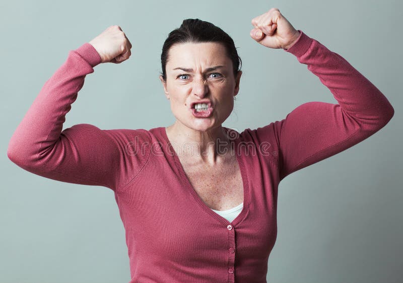 Muscle concept - enraged 40s woman flexing her muscles up for metaphor of female independence and power,studio shot, low contrast effect