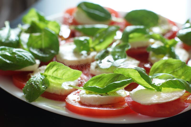 Ensalada caprese clara y hermosa en un plato, una combinación de mozzarella blanca, tomates rojos y hojas verdes de albahaca fresca