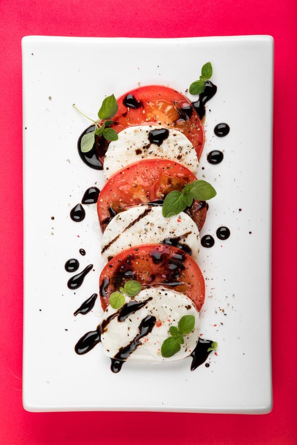 Ensalada de Caprese del italiano con pimienta negra del orégano del tomate de la mozzarella y vinagre balsámico en la placa blanc fotografía de archivo libre de regalías Ensalada de Caprese del italiano con pimienta negra del orégano del tomate de la mozzarella y vinagre balsámico en la placa blanc fotografía de archivo libre de regalías