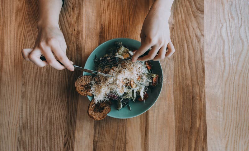 Ensalada de Flatlay con las manos, el cuchillo y la bifurcación de la muchacha imagen de archivo