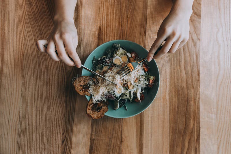 Ensalada de Flatlay con las manos, el cuchillo y la bifurcación de la muchacha fotos de archivo