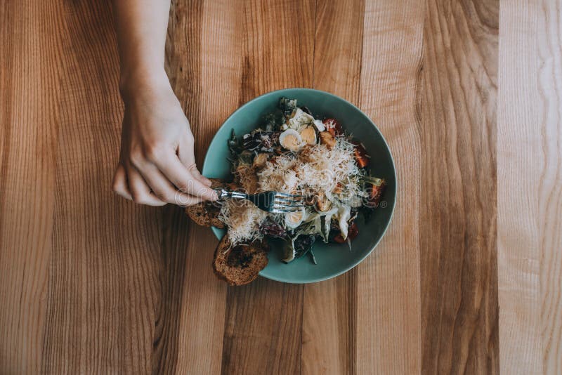 Ensalada de Flatlay con las manos, el cuchillo y la bifurcación de la muchacha fotografía de archivo