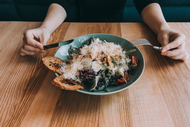 Ensalada de Flatlay con las manos, el cuchillo y la bifurcación de la muchacha foto de archivo