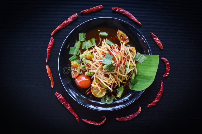 Ensalada de la papaya servida en la comida tailandesa picante del fondo negro/de la ensalada verde de la papaya en la placa con l fotos de archivo libres de regalías