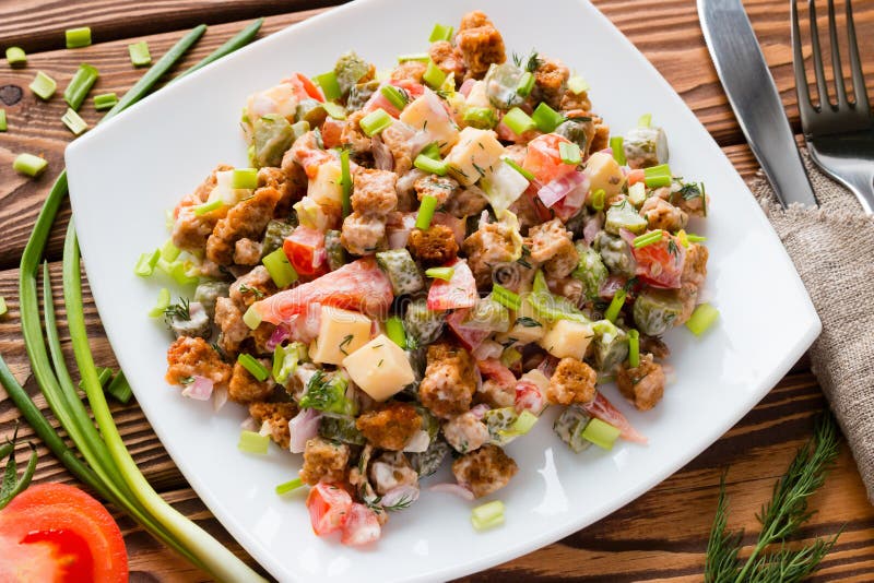 Ensalada de las verduras frescas en una placa blanca con la cebolla verde y el tomate en una tabla fotografía de archivo libre de regalías Ensalada de las verduras frescas en una placa blanca con la cebolla verde y el tomate en una tabla fotografía de archivo libre de regalías