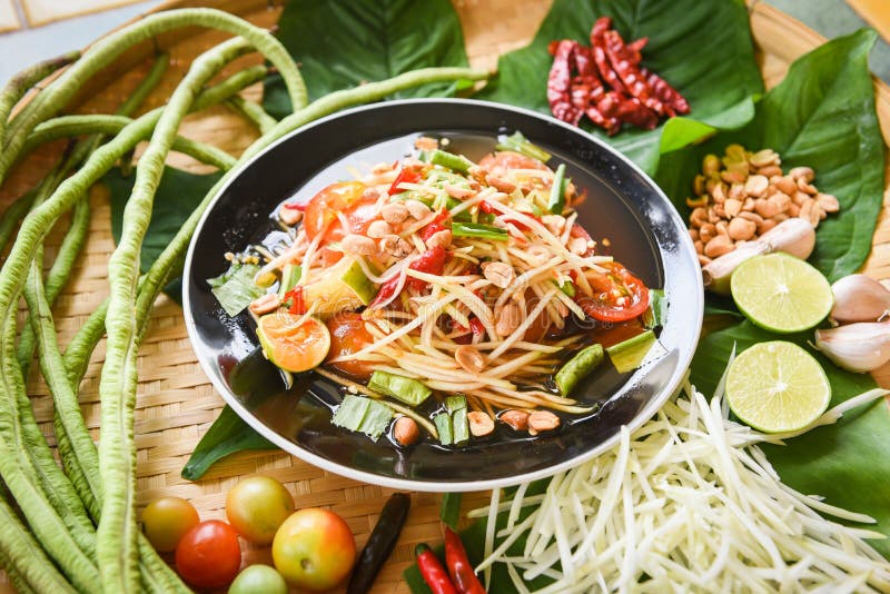 Ensalada de papaya servida en una mesa de madera - Ensalada de papaya verde, comida tailandesa picante en el plato con hierbas de fotografía de archivo libre de regalías