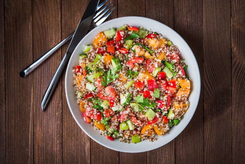 Ensalada sana fresca con la quinoa, los tomates coloridos, la pimienta dulce, el pepino y el perejil en la opinión superior del f foto de archivo libre de regalías Ensalada sana fresca con la quinoa, los tomates coloridos, la pimienta dulce, el pepino y el perejil en la opinión superior del f foto de archivo libre de regalías