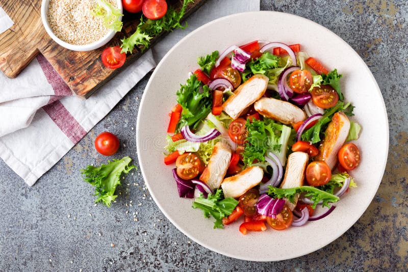 Ensalada vegetal sana con la pechuga de pollo asada a la parrilla, la lechuga fresca, los tomates de cereza, la cebolla roja y la foto de archivo Ensalada vegetal sana con la pechuga de pollo asada a la parrilla, la lechuga fresca, los tomates de cereza, la cebolla roja y la foto de archivo