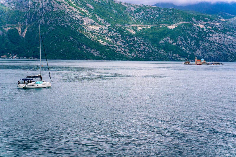 Ensam fartygsegling till fyren av oskulden av klippan i fj?rden av Kotor royaltyfri bild Ensam fartygsegling till fyren av oskulden av klippan i fj?rden av Kotor royaltyfri bild