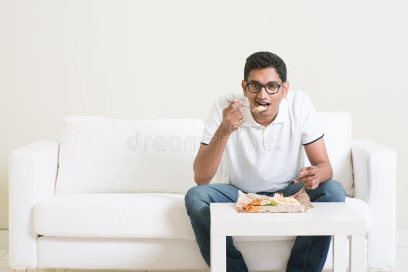 Lonely young single Indian man eating food alone, copy space at side. Having nasi lemak as lunch. Lifestyle of Asian guy at home. Lonely young single Indian man eating food alone, copy space at side. Having nasi lemak as lunch. Lifestyle of Asian guy at home.